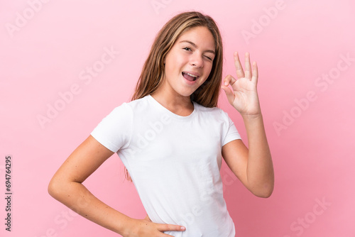 Little caucasian girl isolated on pink background showing ok sign with fingers