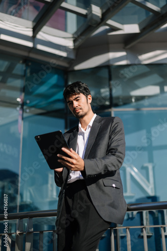 Handsome young businessman using a digital tablet outside an office building..