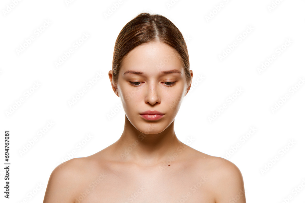 Portrait of beautiful young girl with bare shoulders, well-kept spotless skin looking down isolated white studio background Portrait of beautiful young girl with bare shoulders, well-kept spotless skin looking down isolated white studio background