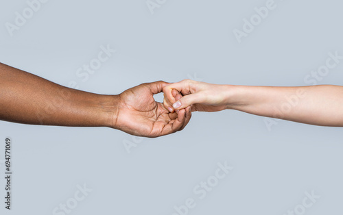 White Caucasian female hands and black african american holding fingers together. Woman and african woman hand. Helping hand, rescue. Helping hands, rescue gesture. Black and white human hands