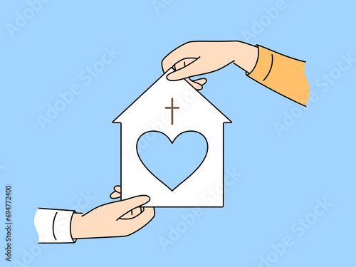 Model of christian church with heart in mans hand for advertising catholic charitable foundation providing assistance to people in need. Concept of volunteer assistance to christian churches