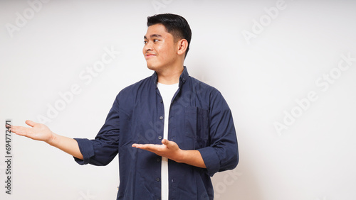 Young Asian man smiling when looking and pointing to the right side on white background. studio shot photo