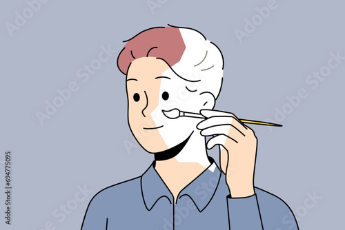 Self-sufficient man artist paints own face and hair with brush, creating self-portrait. Self-sufficient guy draws look, for concept of independence and personal improvements thanks to fortitude