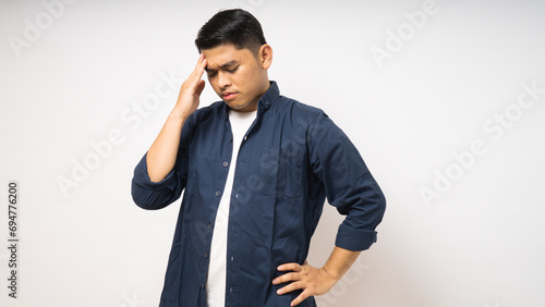 Asian young man showing in pain expression while touching his head