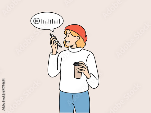 Woman is recording voice messages holding phone and plastic glass of coffee in hands. Beautiful girl uses voice messages to communicate with friends via internet or post on social networks