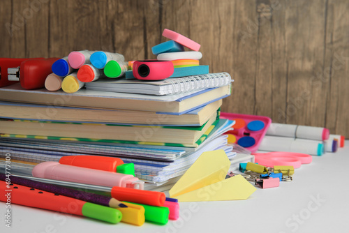 Many different books, paper plane and school stationery on white table, closeup. Back to school