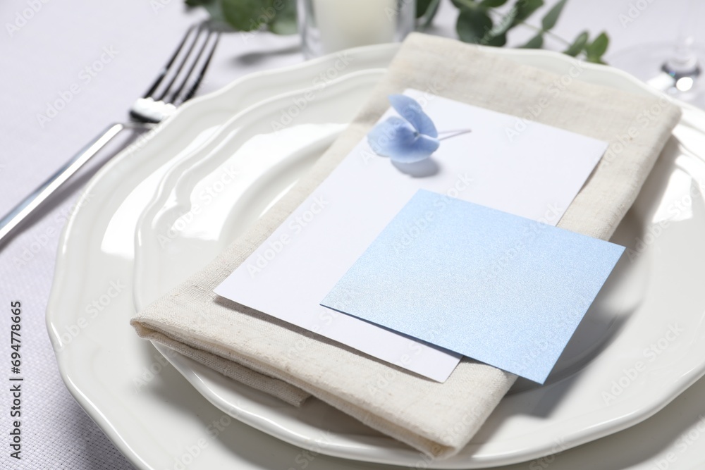 Beautiful table setting with blank card and floral decor, closeup Beautiful table setting with blank card and floral decor, closeup