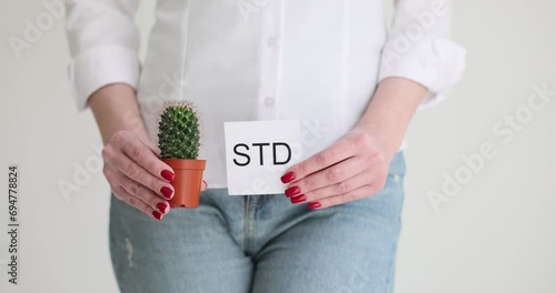 The girl holds a cactus and a sheet of paper, it is written by STD. The consequences of sexually transmitted diseases photo