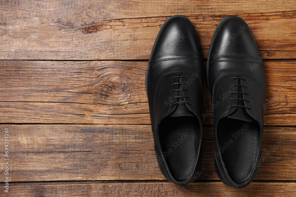 Pair of black leather men shoes on wooden background, top view. Space for text Pair of black leather men shoes on wooden background, top view. Space for text