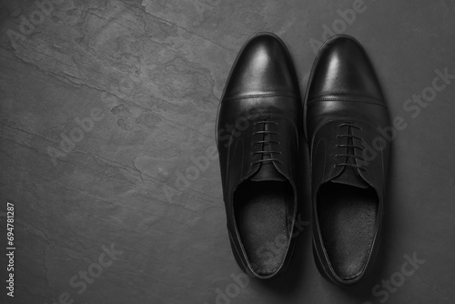 Pair of leather men shoes on black surface, top view. Space for text