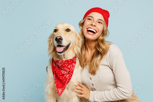 Young minded owner woman wear casual clothes red hat bandana hug cuddle embrace her best friend retriever dog look aside isolated on plain pastel blue background studio. Take care about pet concept photo