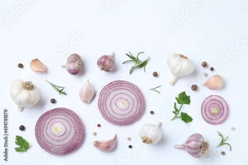 Fresh garlic, onion rings and spices on white table, flat lay