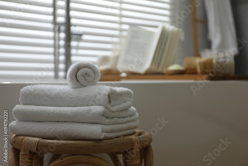 Wooden tray with spa products and book on bath tub in bathroom, selective focus