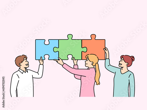 Teamwork of business people putting together puzzle to jointly solve problem of increasing company profits. Teamwork of man and two women experiencing sense of unity and desire to help colleagues