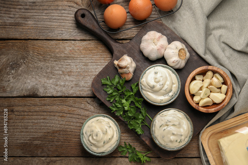 Tasty sauce with garlic and ingredients on wooden table, flat lay. Space for text photo