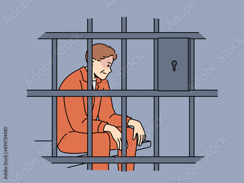 Man criminal sits in prison cell and is sad because of unfair court decision or lack of right to amnesty. Prisoner is serving prison sentence in correctional facility after committing illegal acts.