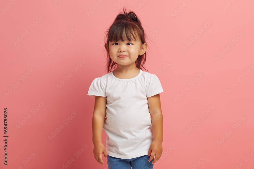 Handsome three years old little asian girl wearing in white shirt standing on a pink isolated. Handsome three years old little asian girl wearing in white shirt standing on a pink isolated.