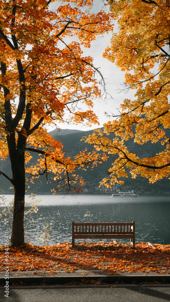 Beautiful fall scenery in Zell am See, Austria with bench, golden foliage and ship on a lake, Salzburg Land, Austria