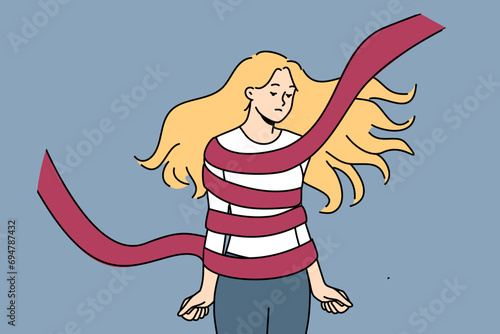 Woman hostage tied with rope is sad and clenches fists, feeling helplessness and crippling apathy. Teenage girl hostage needs help to get rid of shackles and stop being victim of violence