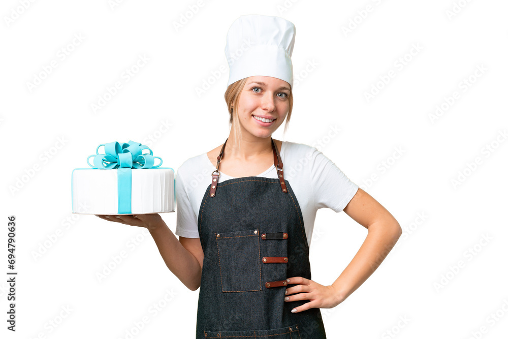 Young pastry blonde woman with a big cake over isolated chroma key background posing with arms at hip and smiling Young pastry blonde woman with a big cake over isolated chroma key background posing with arms at hip and smiling