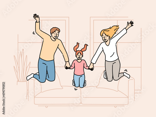 Happy family jumping together in living room of own apartment after moving or buying new home. Joyful family of loving mother and father with little daughter became owners of cozy apartment