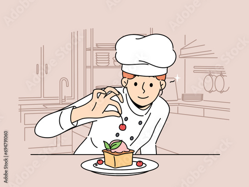 Woman pastry chef prepares dessert cake with fresh berries standing in kitchen of restaurant or bakery. Girl decorates cheesecake with cherry before serving dessert to cafeteria customer.