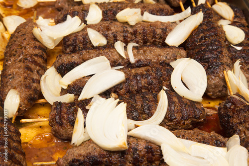 Grilled meat on wooden skewers sprinkled with onions close-up. Lula - kebab.