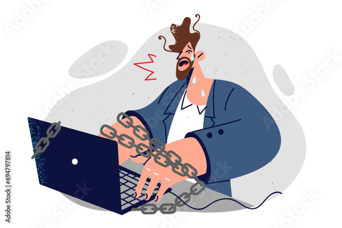 Corporate slave is crying sitting at computer with chains and feeling tired or professional burnout