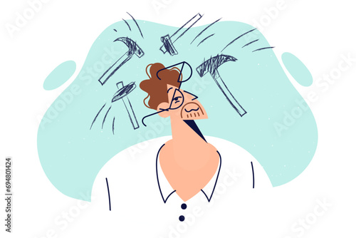 Man suffers from headache due to intracranial pressure problems standing among hammers