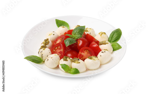 Plate of tasty Caprese salad with mozzarella, tomatoes, basil and pesto sauce isolated on white