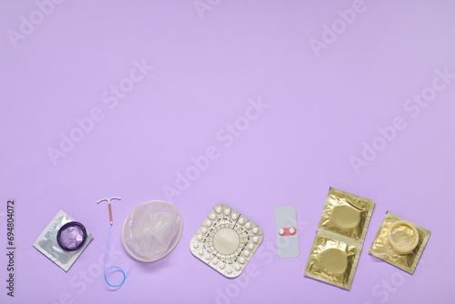 Contraceptive pills, condoms and intrauterine device on lilac background, flat lay and space for text. Different birth control methods