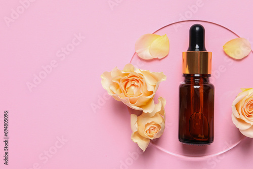 Bottle of cosmetic serum, flowers and petals on pink background, flat lay. Space for text