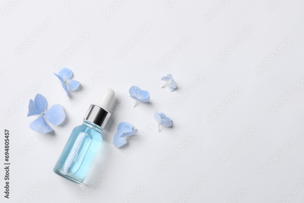 Bottle of cosmetic serum and beautiful flowers on white background, flat lay. Space for text Bottle of cosmetic serum and beautiful flowers on white background, flat lay. Space for text