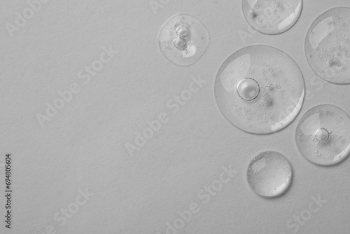 Samples of cosmetic serum on light grey background, top view. Space for text