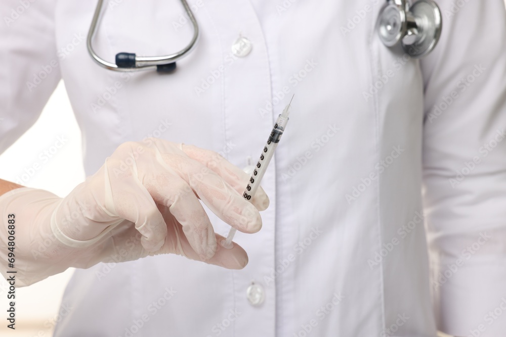 Doctor holding medical syringe on white background, closeup Doctor holding medical syringe on white background, closeup
