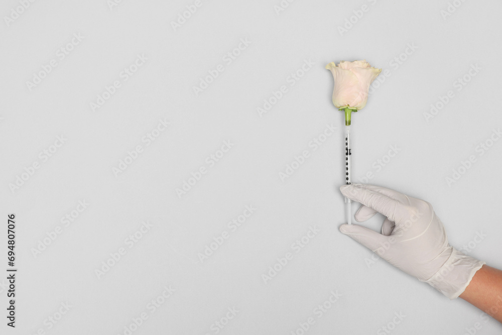Doctor making injection to rose on light grey background, top view. Space for text