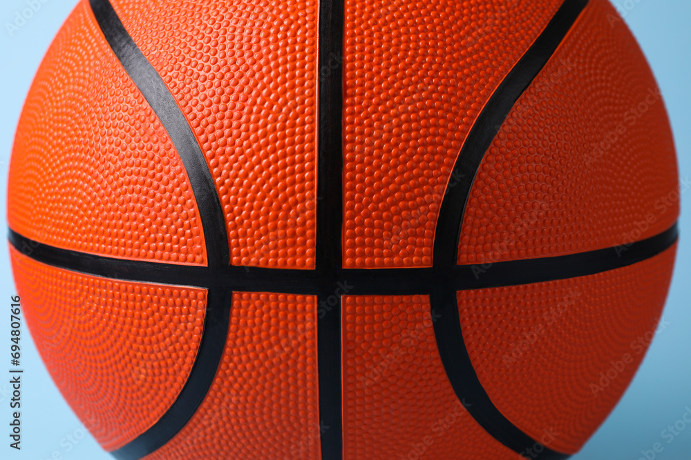 Obraz premium One orange basketball ball on light blue background, closeup