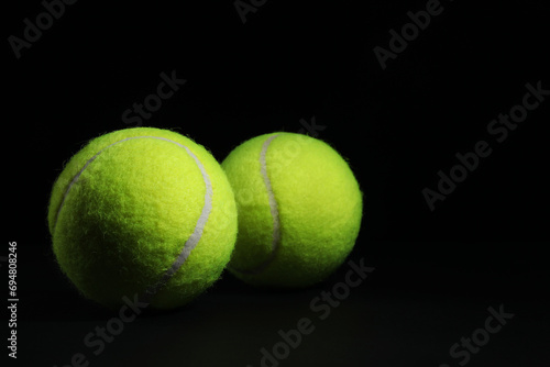 Two tennis balls on black background, closeup. Space for text © New Africa