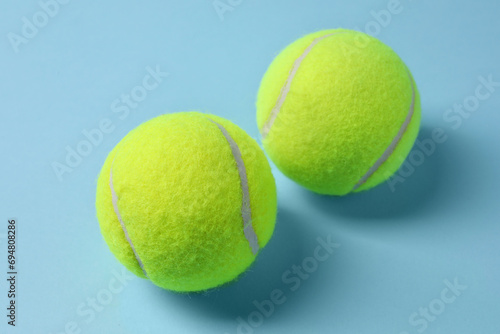 Two tennis balls on light blue background, closeup