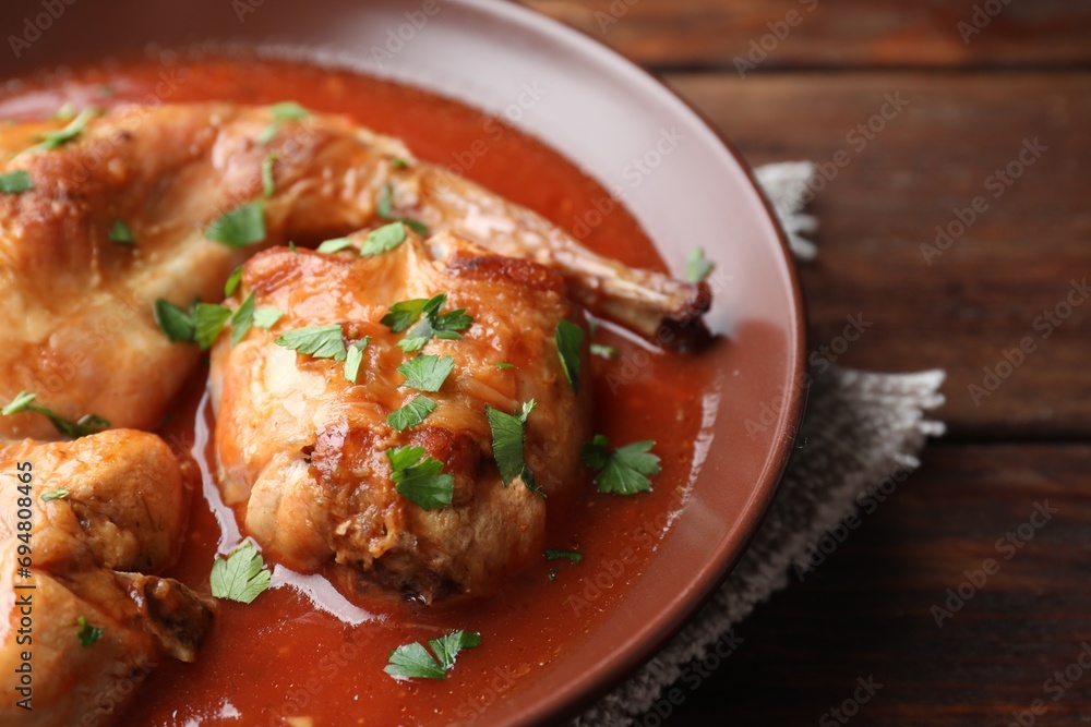 Tasty cooked rabbit meat with sauce and parsley on wooden table, closeup Tasty cooked rabbit meat with sauce and parsley on wooden table, closeup