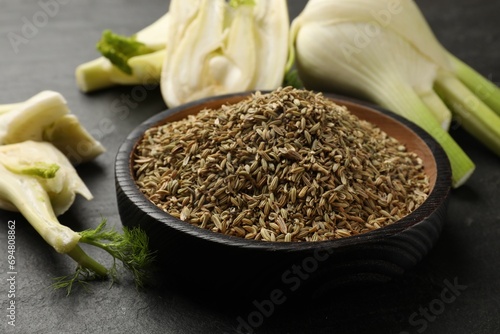 Fresh fennel bulbs and seeds in bowl on gray table, closeup