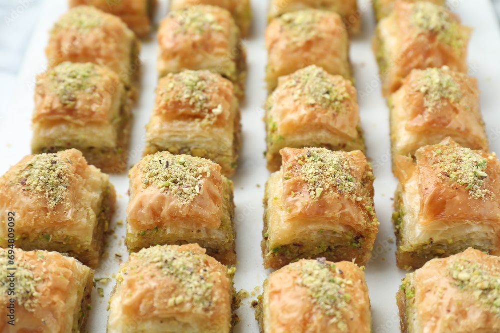 Delicious fresh baklava with chopped nuts on white table, closeup. Eastern sweets