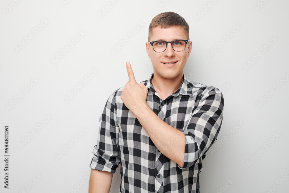Handsome man in glasses pointing aside finger, demonstrating empty space for product or text isolated on white studio background. Handsome man in glasses pointing aside finger, demonstrating empty space for product or text isolated on white studio background.