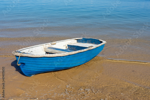 Blue and white row boat on the sandy shore of the calm blue sea. Main Beach, Coochiemudlo Island, Queensland, Australia photo