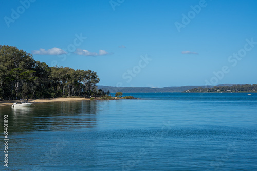 View across calm water to the sandy shore of Coochiemudlo Island, with Macleay Island and Stradbroke Island in the distance.
