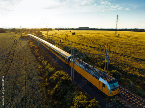 Aerial view of train in the middle of nature, field, during autumn sunny day.