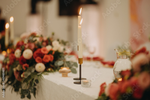 Elegant, romantic table setting for indoor wedding reception. Luxury wedding table decoration, special event table set up with fresh flowers arragements and high candlestick, candle holder.