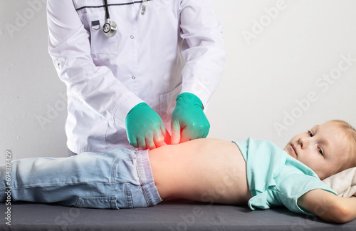 A doctor in green medical gloves is palpating the abdomen of a little seven-year-old girl. Stomach disease, gastritis and peptic ulcer in children, indigestion. Copy space for text photo