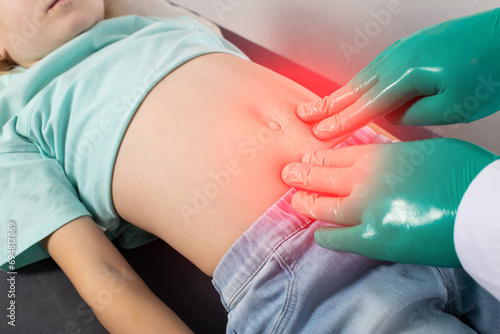 A doctor palpates the abdomen of a seven-year-old little girl who has pain and colic in her abdomen. Concept of intestinal diseases in children, spasms and diarrhea, close-up