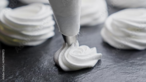 Process of making Cake Anna Pavlova. Confectioner makes meringue for cake. Baker spread meringue on baking sheet with a pastry bag. Close-up in 4K, UHD photo